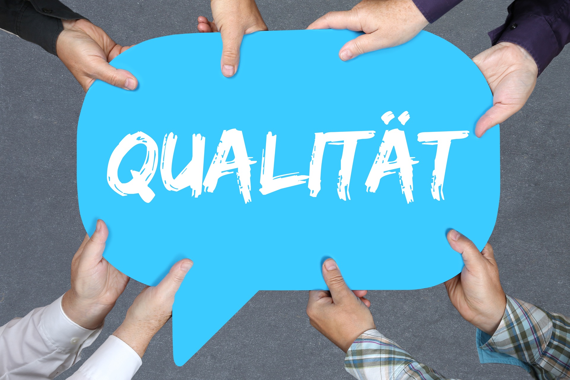 Mehrere Haende halten ein Schild mit dem Wort Qualität | klinische Bewertung
